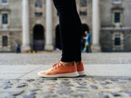 Ein Paar orangefarbene Low-Top-Schuhe auf hellem Untergrund, minimalistisch inszeniert, Fokus auf Farbe und Form