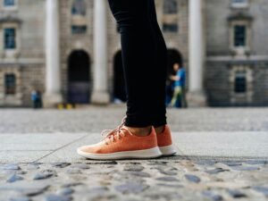 Ein Paar orangefarbene Low-Top-Schuhe auf hellem Untergrund, minimalistisch inszeniert, Fokus auf Farbe und Form