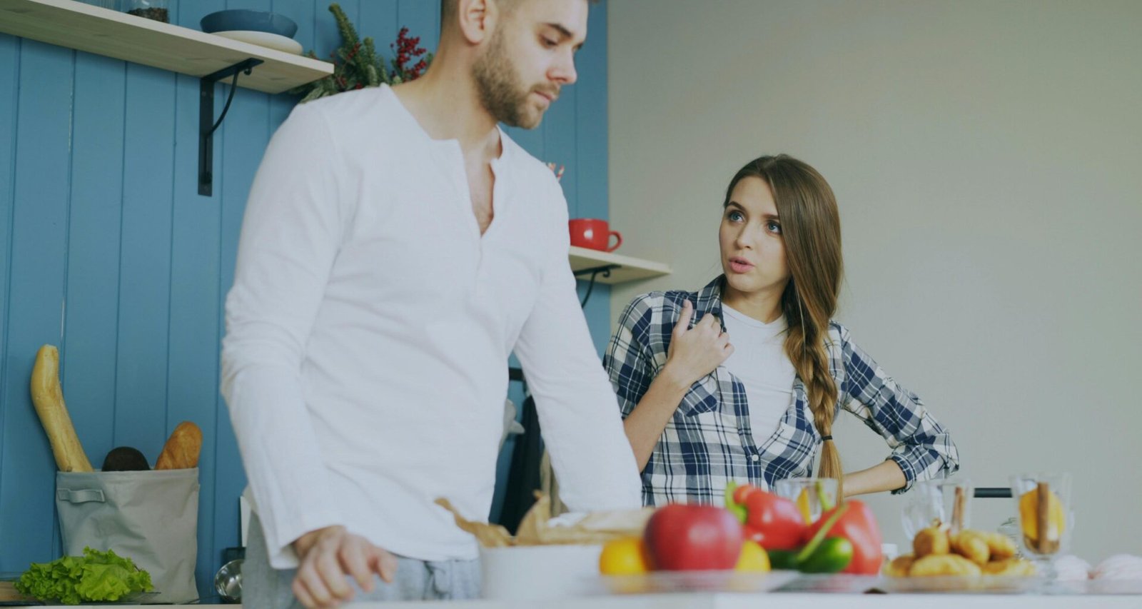 Ein Mann und eine Frau streiten in einer modernen Küche und stehen sich gegenüber am Küchentisch