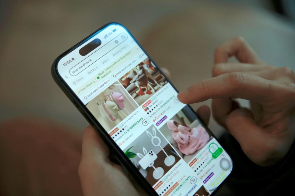 Eine Person scrollt auf einem Smartphone durch eine Online-Shopping-App und betrachtet Produktangebote.