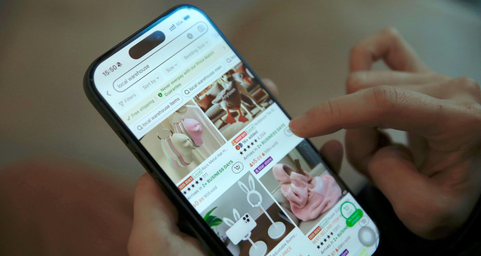 Eine Person scrollt auf einem Smartphone durch eine Online-Shopping-App und betrachtet Produktangebote.