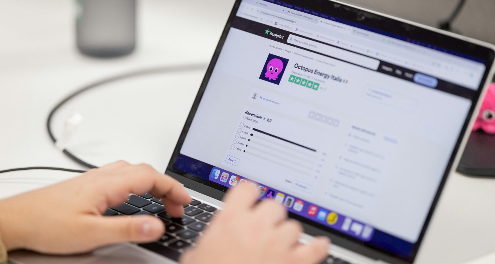 Person tippt auf einer Laptop-Tastatur mit geöffnetem Bildschirm an einem Schreibtisch im Büro