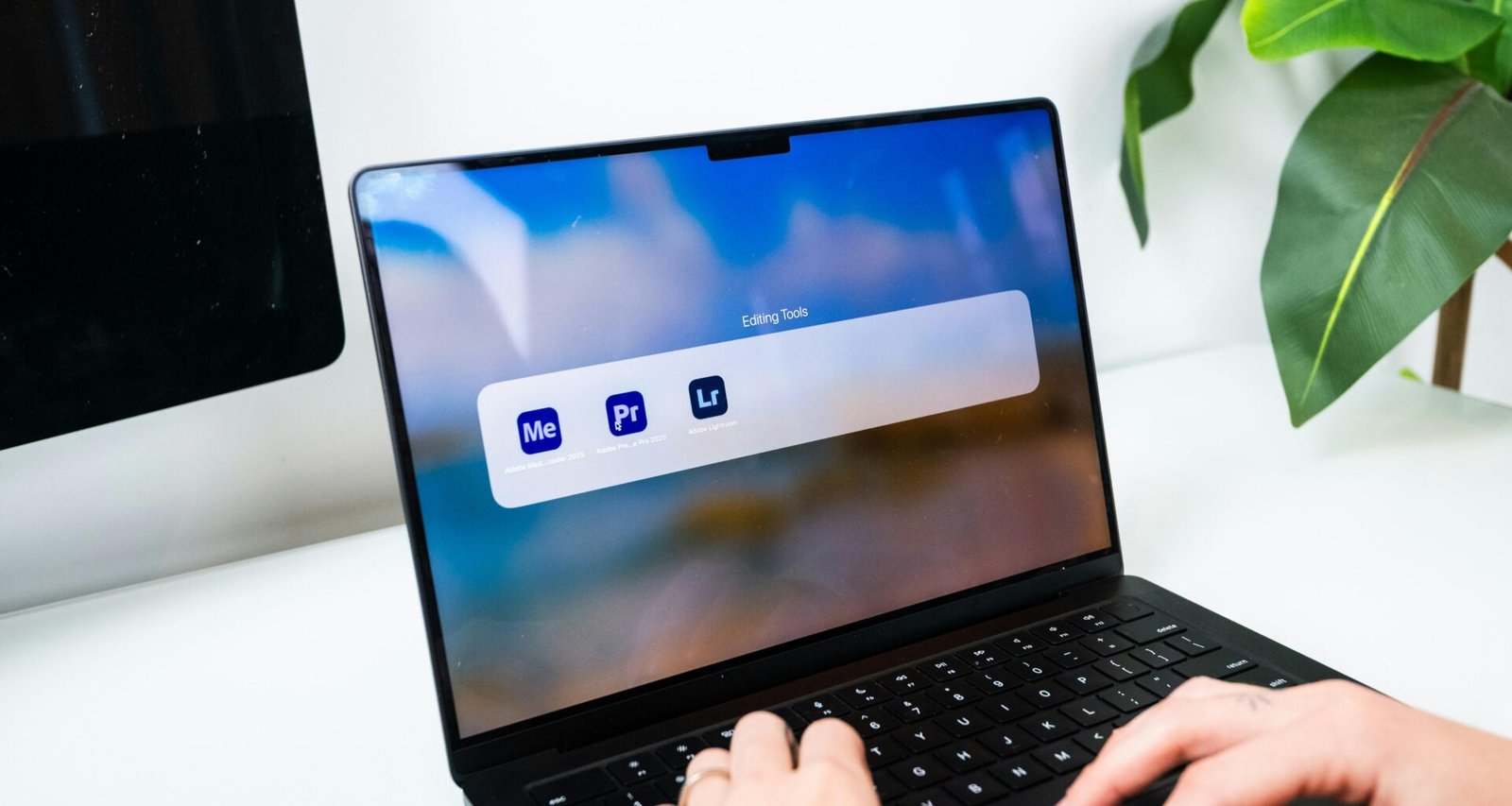 Person tippt auf einem Laptop, während verschiedene Software-Icons auf dem Bildschirm angezeigt werden.