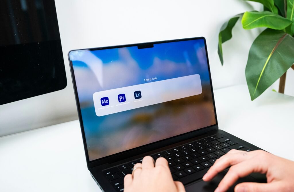 Person tippt auf einem Laptop, auf dem verschiedene Software-Icons auf dem Bildschirm zu sehen sind
