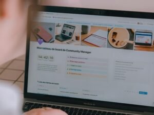 Eine Person sitzt an einem Schreibtisch und blickt konzentriert auf den Bildschirm eines aufgeklappten Laptops mit geöffneter Website.