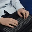 Person tippt konzentriert auf einer Laptop-Tastatur während der Arbeit am Schreibtisch