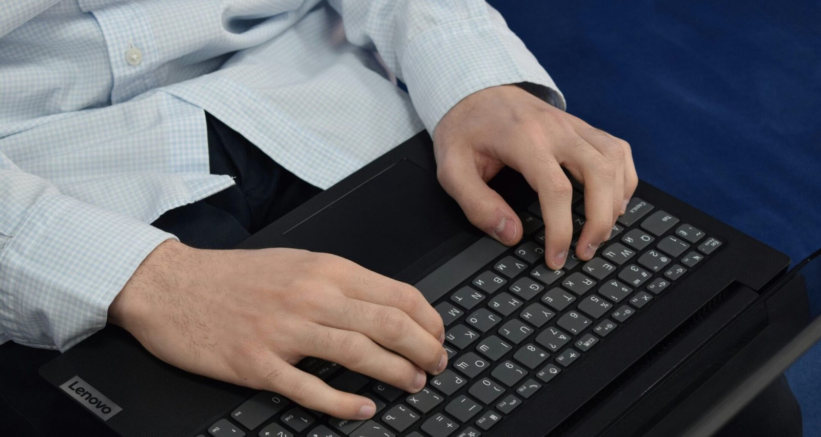 Person tippt konzentriert auf einer Laptop-Tastatur während der Arbeit am Schreibtisch