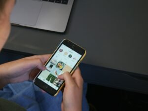 Eine Person hält ein iPhone in der Hand und tippt darauf, symbolisch für mobile Technik im modernen Alltag