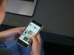 Person hält ein iPhone in der Hand und nutzt das Smartphone, Fokus auf das Gerät und die Hand des Nutzers