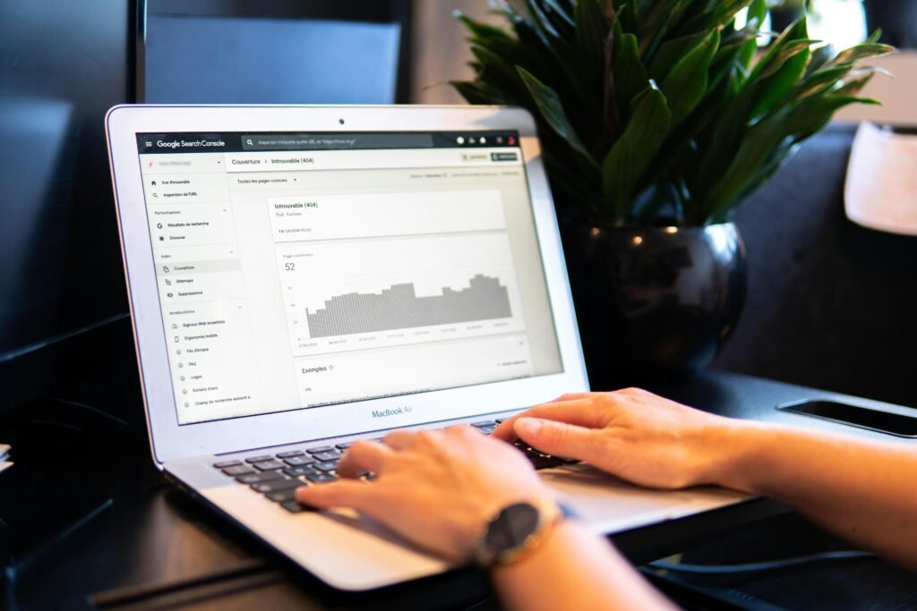 Person arbeitet am MacBook Air auf einem braunen Holztisch mit moderner Technik und digitalem Arbeitsplatz