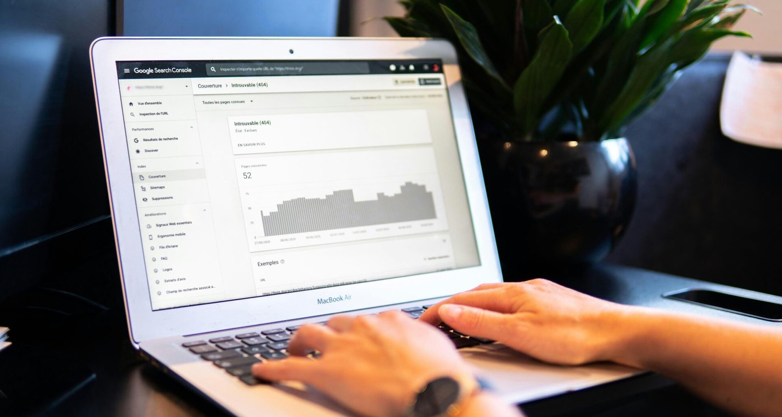 Person verwendet ein MacBook Air auf einem braunen Holztisch bei der Arbeit, Fokus auf digitale Produktivität und Technik.