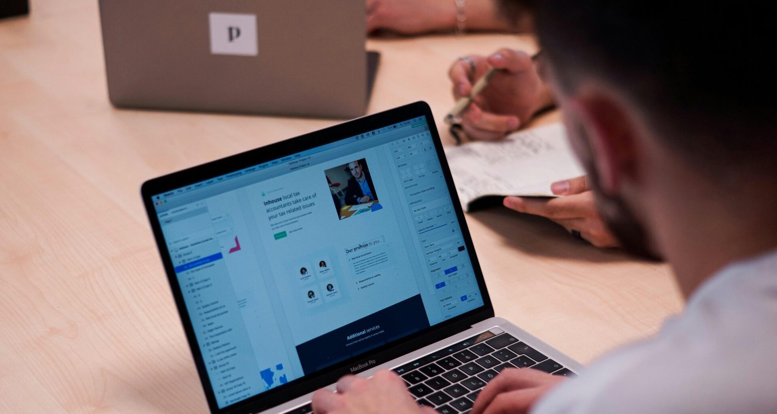 Person sitzt an einem Tisch und benutzt ein MacBook Pro Laptop für die Arbeit in einer modernen Umgebung