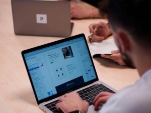 Person sitzt an einem Tisch und benutzt ein MacBook Pro Laptop für die Arbeit in einer modernen Umgebung