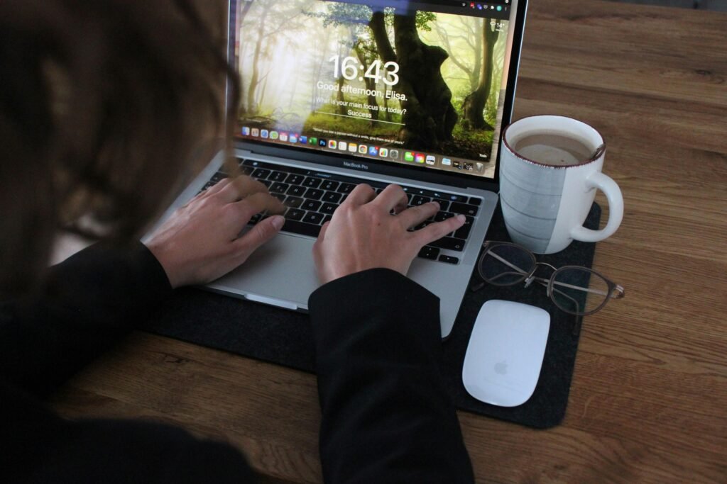 Person benutzt ein MacBook Pro auf einem braunen Holztisch, ideal für produktives Arbeiten im digitalen Bereich.