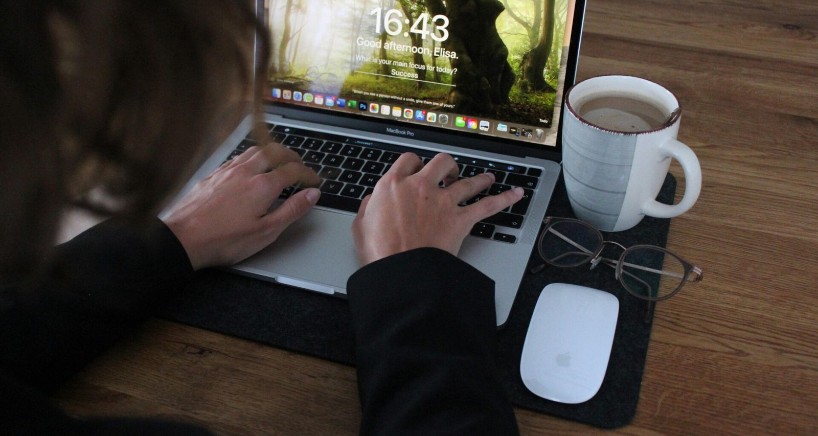 Person benutzt ein MacBook Pro auf einem braunen Holztisch, ideal für produktives Arbeiten im digitalen Bereich.