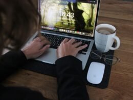 Person benutzt ein MacBook Pro auf einem braunen Holztisch, ideal für produktives Arbeiten im digitalen Bereich.