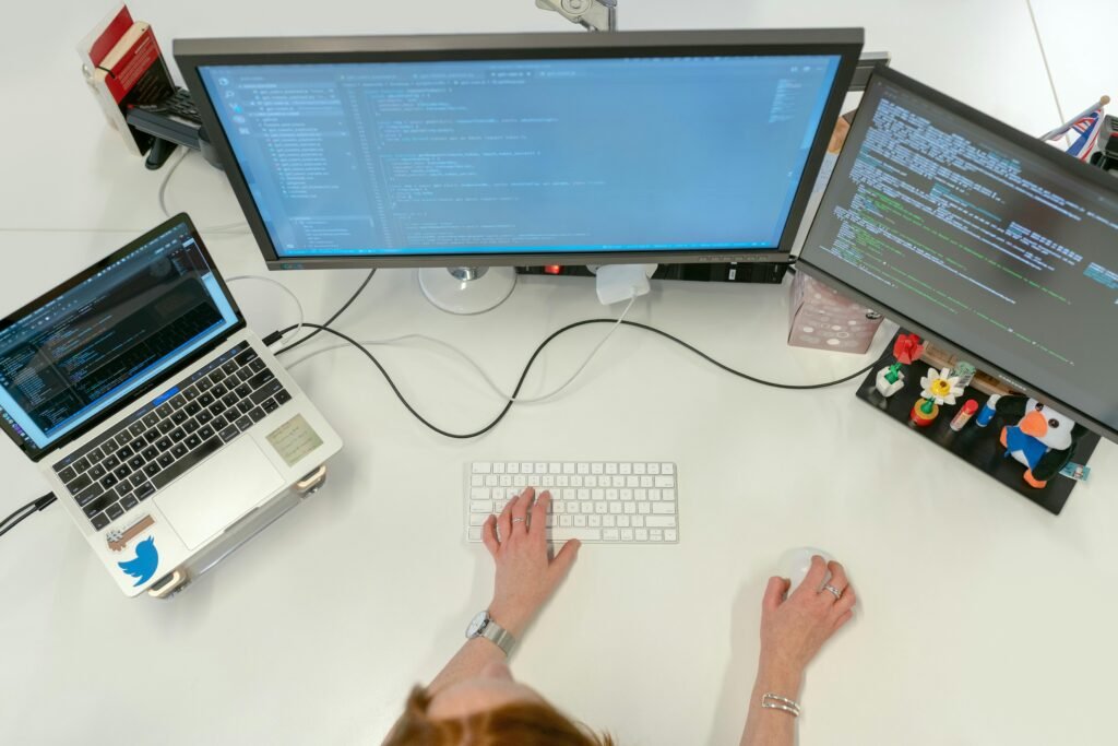 Person arbeitet an einem MacBook Pro auf einem weißen Tisch, ideal für Beiträge zu digitalen Arbeitsprozessen oder Online-Marketing.