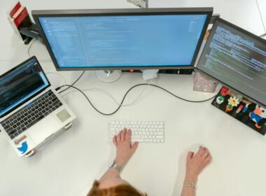 Person nutzt ein MacBook Pro auf einem weißen Tisch in einer modernen Arbeitsumgebung mit Fokus auf Technologie.