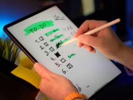 Person arbeitet mit Stylus auf Tablet und setzt Häkchen auf einer digitalen To-Do-Liste zur Aufgabenorganisation.