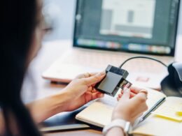 Nahaufnahme einer Hand, die eine Speicherkarte sorgfältig in einen Kartenleser einführt, Fokus auf Gerät und Karte