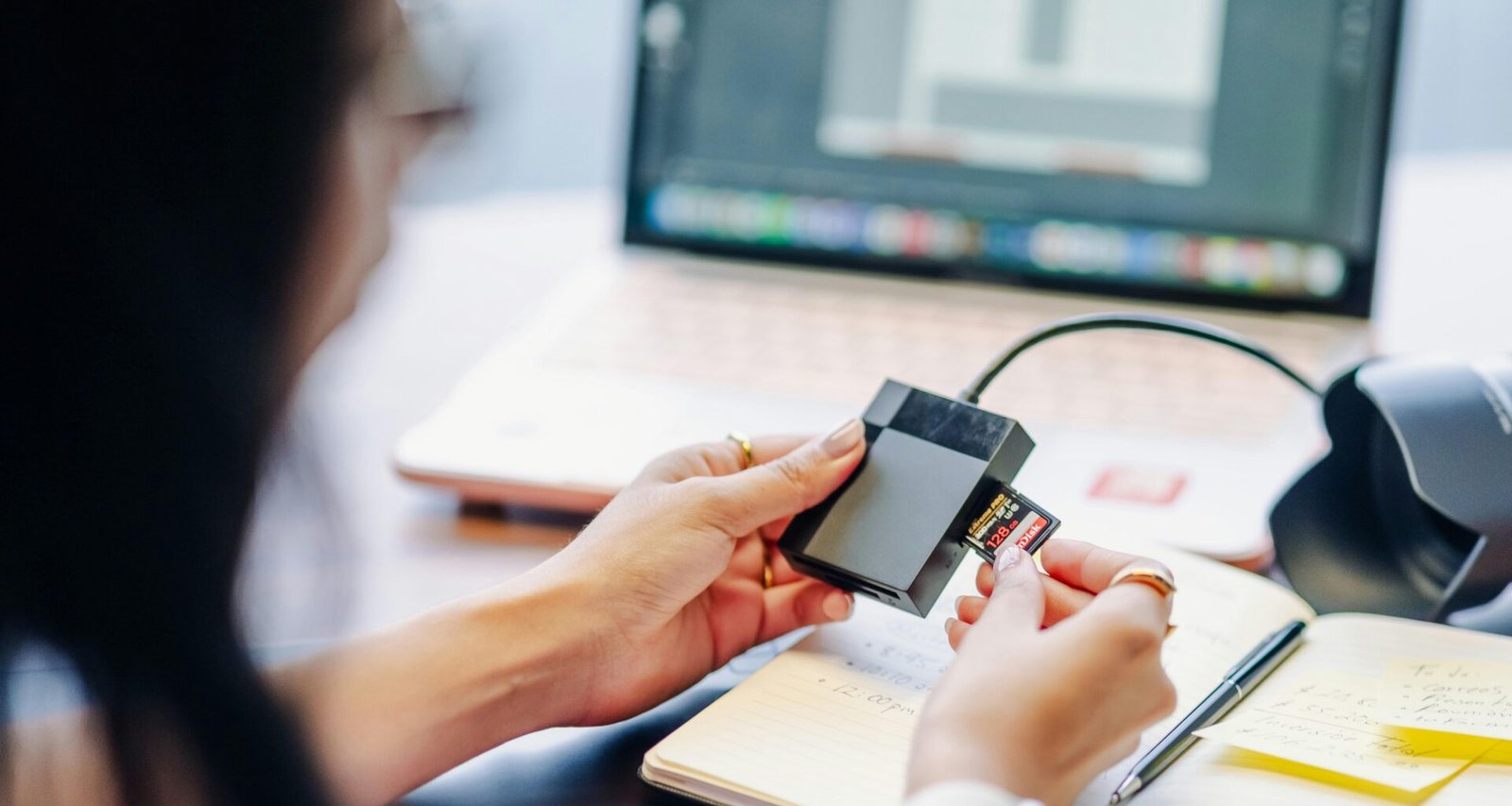 Eine Person steckt vorsichtig eine Speicherkarte in einen Kartenleser, um Daten zwischen Geräten auszutauschen.