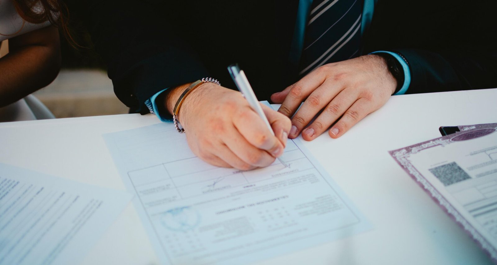 Eine Person unterschreibt ein wichtiges Dokument mit einem Kugelschreiber an einem Tisch im Büro.