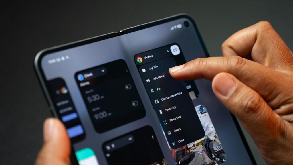 Person hält ein aufgeklapptes, faltbares Smartphone und bedient mehrere geöffnete Apps gleichzeitig