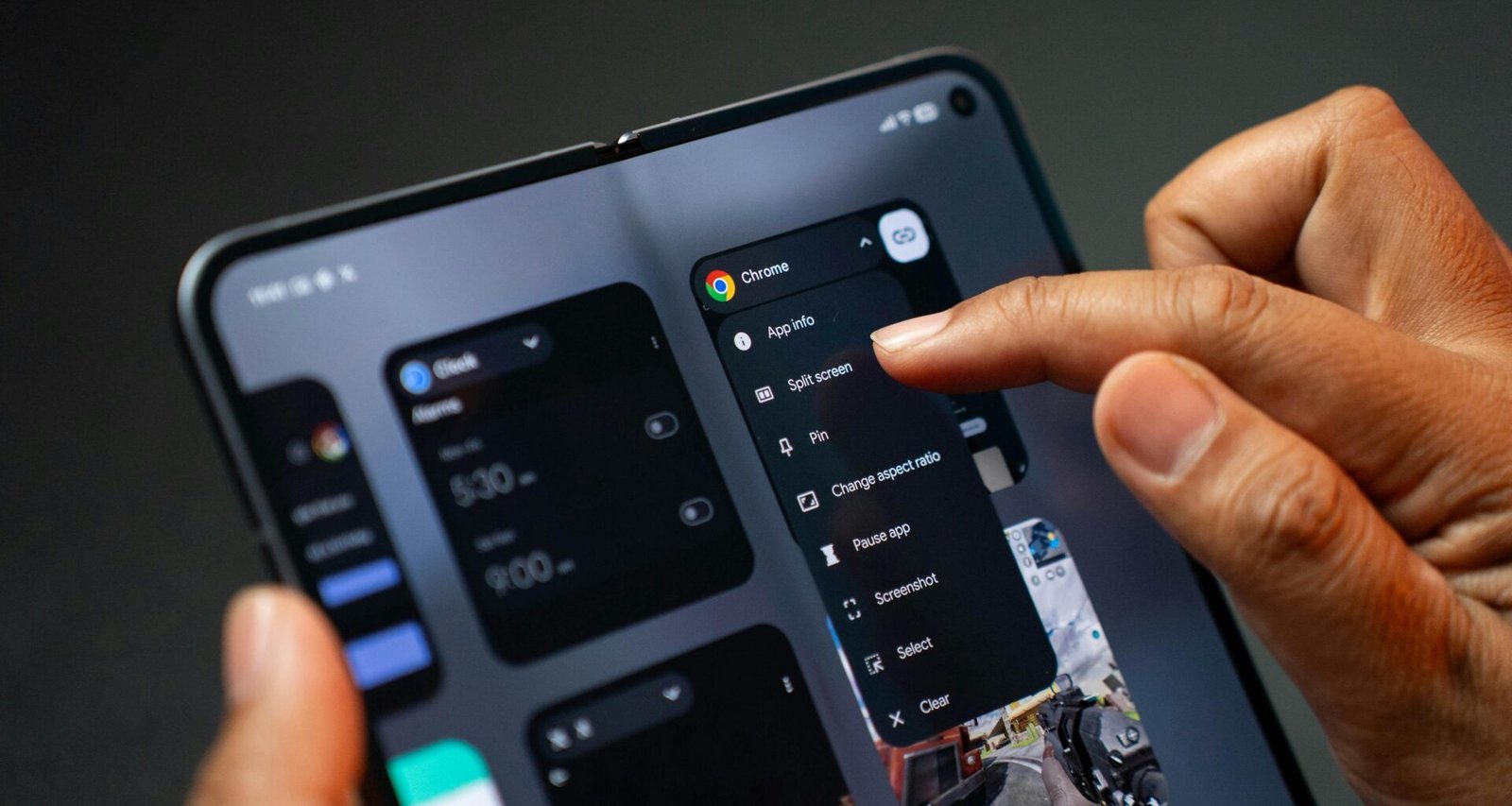 Person hält ein aufgeklapptes, faltbares Smartphone und bedient mehrere geöffnete Apps gleichzeitig