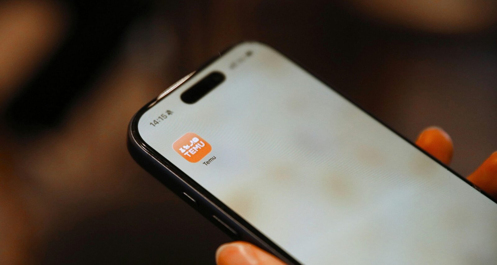 Nahaufnahme einer Hand, die ein Smartphone hält, auf dessen Bildschirm ein App-Symbol deutlich zu sehen ist.