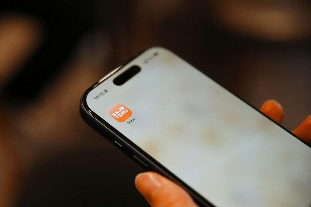 Eine Person hält ein Smartphone in der Hand, auf dem ein farbiges App-Symbol auf dem Display zu sehen ist.