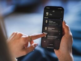 Person hält ein Smartphone mit einer angezeigten Listenansicht in der Hand, fokussiert auf digitale Organisation und Produktivität