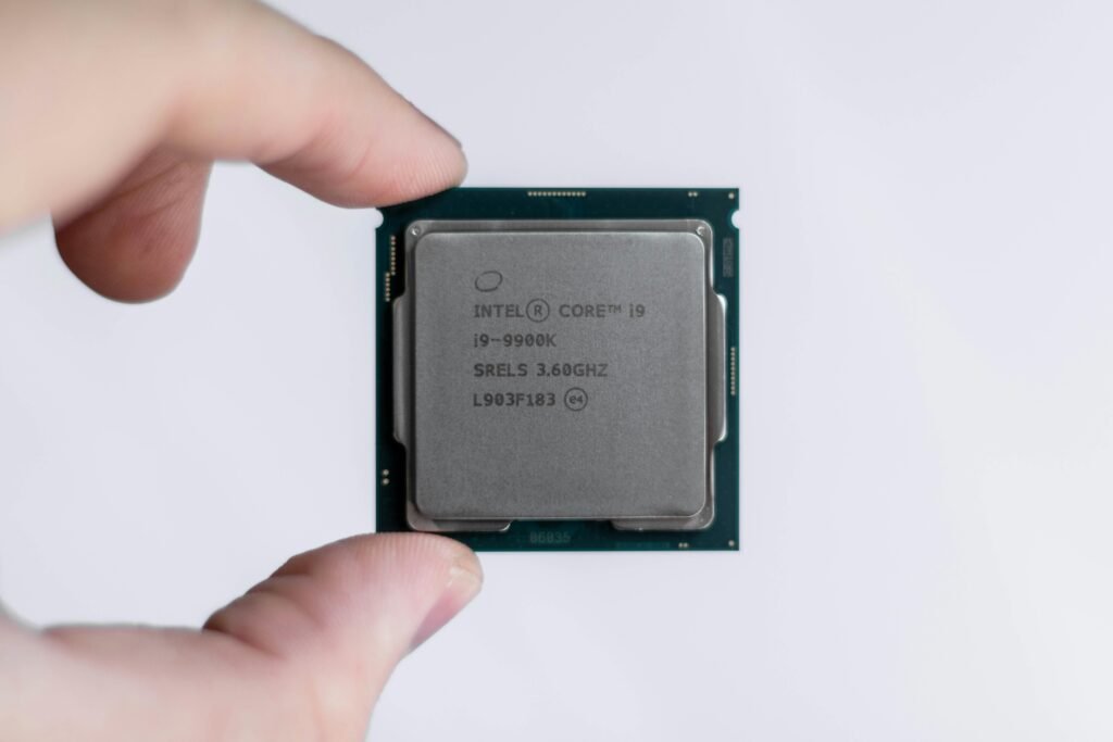 Eine Person hält einen Intel-Prozessor zwischen den Fingern. Der Prozessor ist im Fokus und wird von Hand präsentiert.