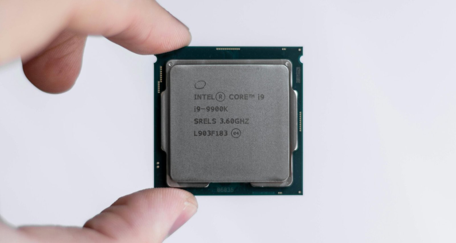 Eine Person hält einen Intel-Prozessor zwischen den Fingern. Der Prozessor ist im Fokus und wird von Hand präsentiert.