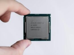 Eine Person hält einen Intel-Prozessor zwischen den Fingern. Der Prozessor ist im Fokus und wird von Hand präsentiert.
