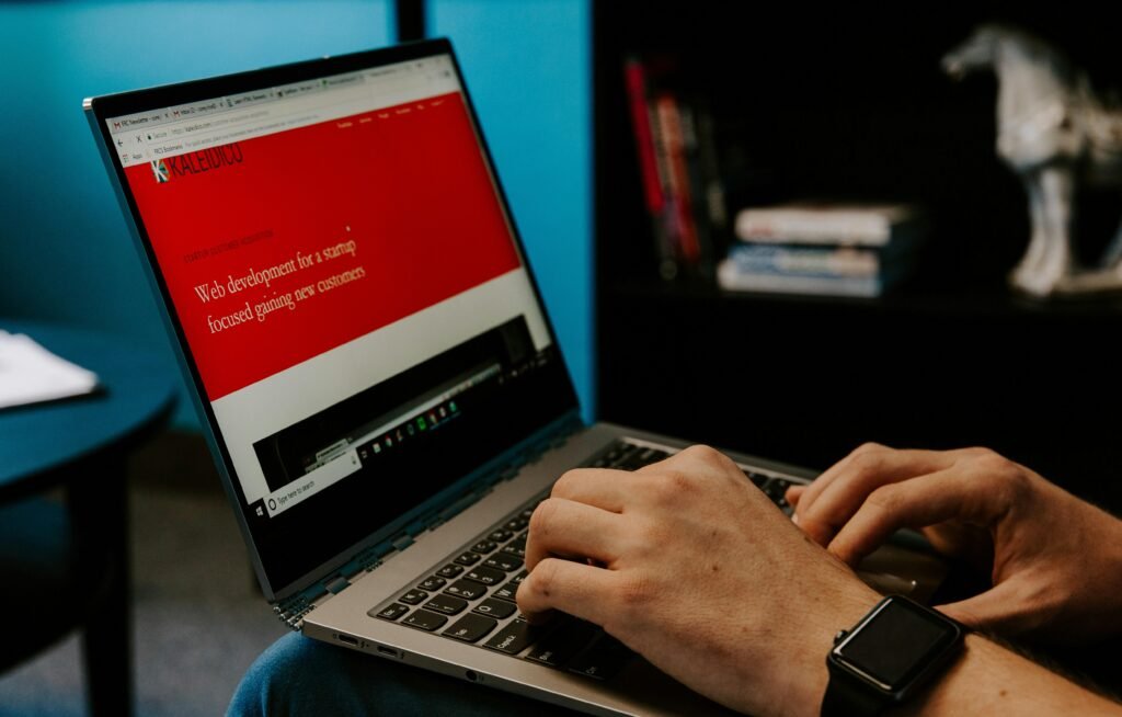 Eine Person sitzt mit einem Laptop in einem hellen Raum und arbeitet konzentriert am Schreibtisch
