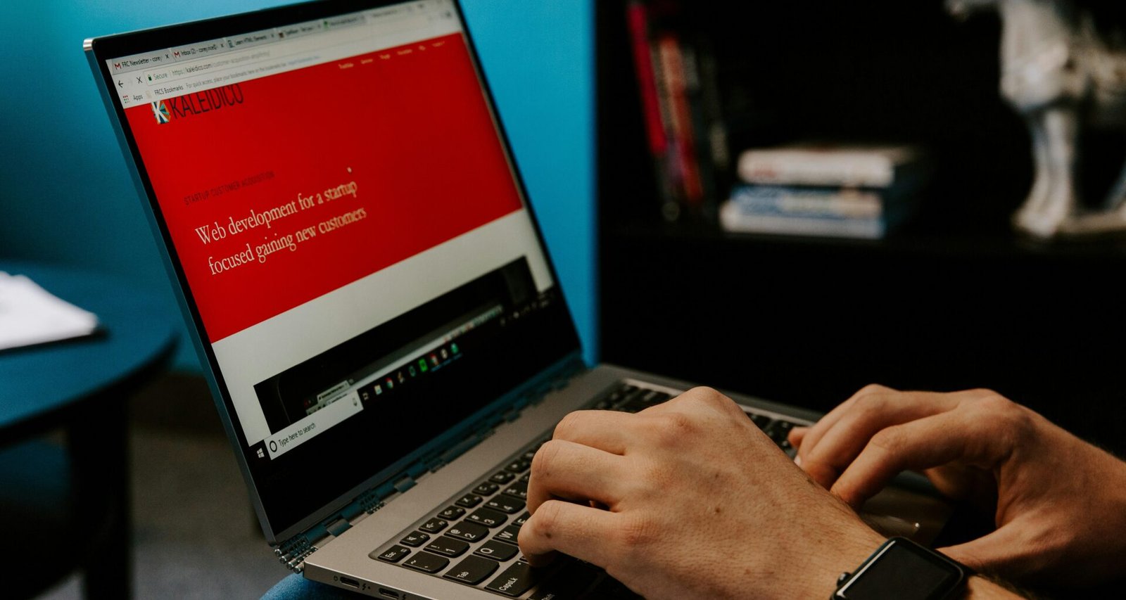 Eine Person sitzt mit einem Laptop in einem hellen Raum und arbeitet konzentriert am Schreibtisch