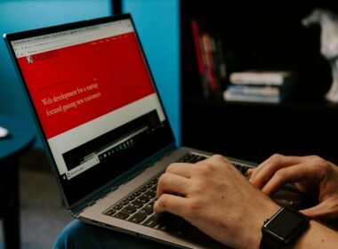 Eine Person sitzt mit einem Laptop in einem hellen Raum und arbeitet konzentriert am Schreibtisch