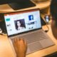 Person sitzt an einem Tisch und verwendet ihren Laptop, um durch die Facebook-Anwendung im Browser zu navigieren.
