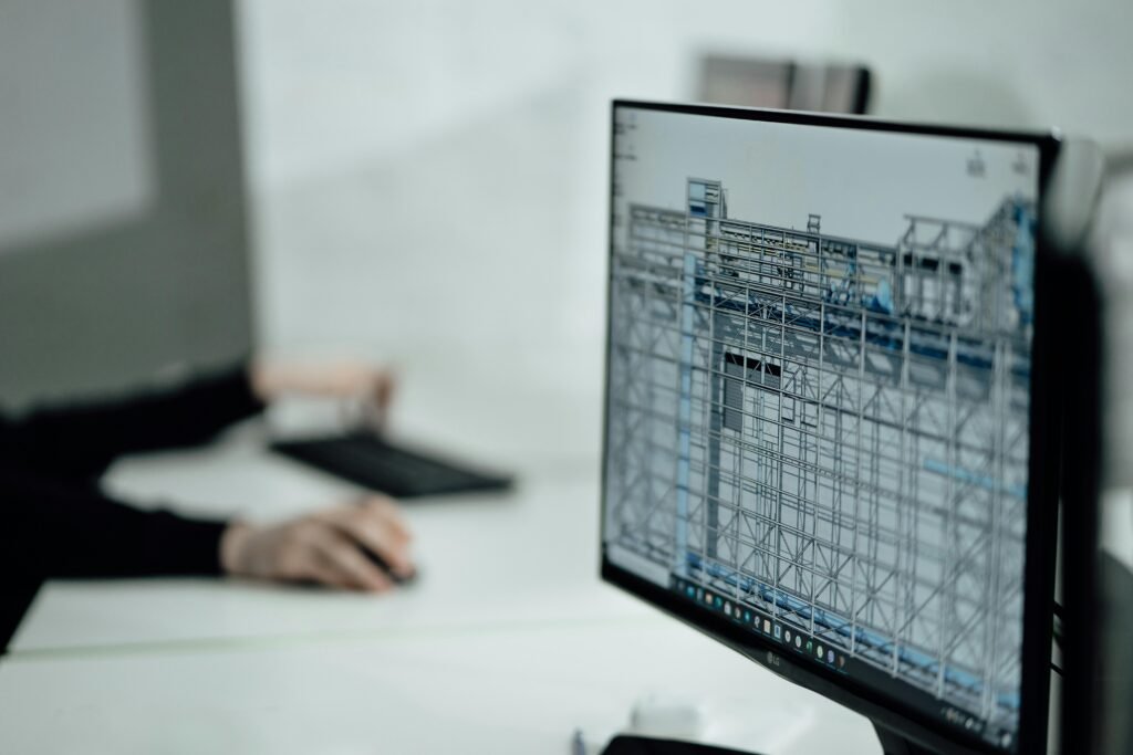 Person sitzt an einem Tisch und verwendet ein schwarzes Laptop, Fokus auf Technik und Arbeitssituation