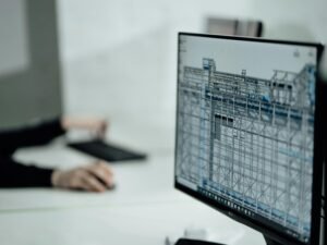 Person sitzt an einem Tisch und verwendet ein schwarzes Laptop, Fokus auf Technik und Arbeitssituation