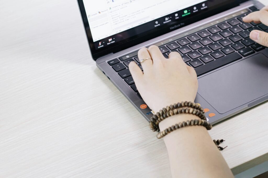 Eine Person nutzt einen schwarzen und silbernen Laptop auf einem Tisch, um digitale Aufgaben zu erledigen.