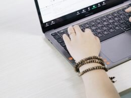 Eine Person nutzt einen schwarzen und silbernen Laptop auf einem Tisch, um digitale Aufgaben zu erledigen.