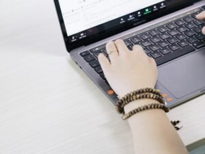 Eine Person arbeitet an einem schwarzen und silbernen Laptop an einem Tisch, moderne Technologie im Geschäftsalltag