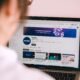 Person betrachtet auf dem Laptop einen YouTube-Kanal und informiert sich über Video-Marketing am Schreibtisch