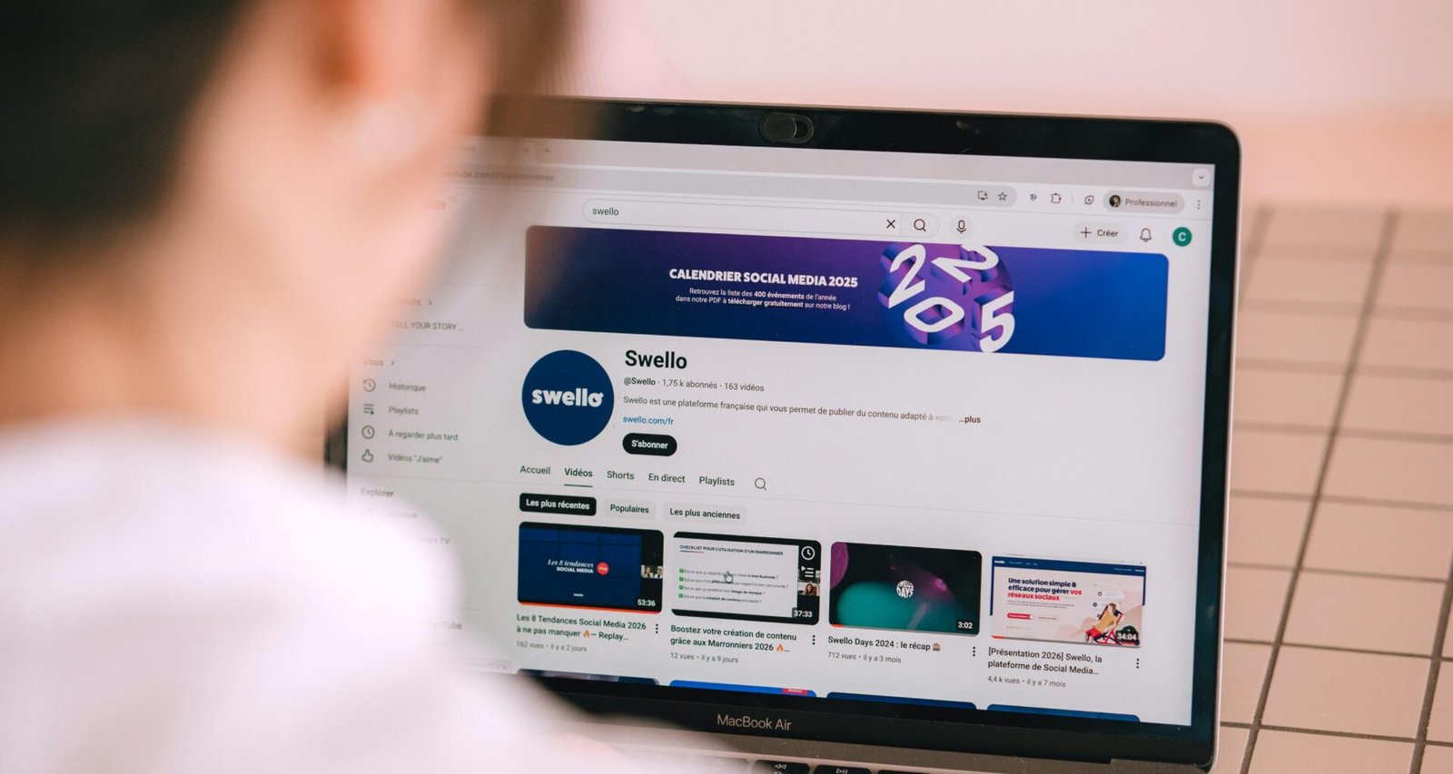 Person streamt einen YouTube-Kanal auf einem aufgeklappten Laptop an einem Arbeitstisch