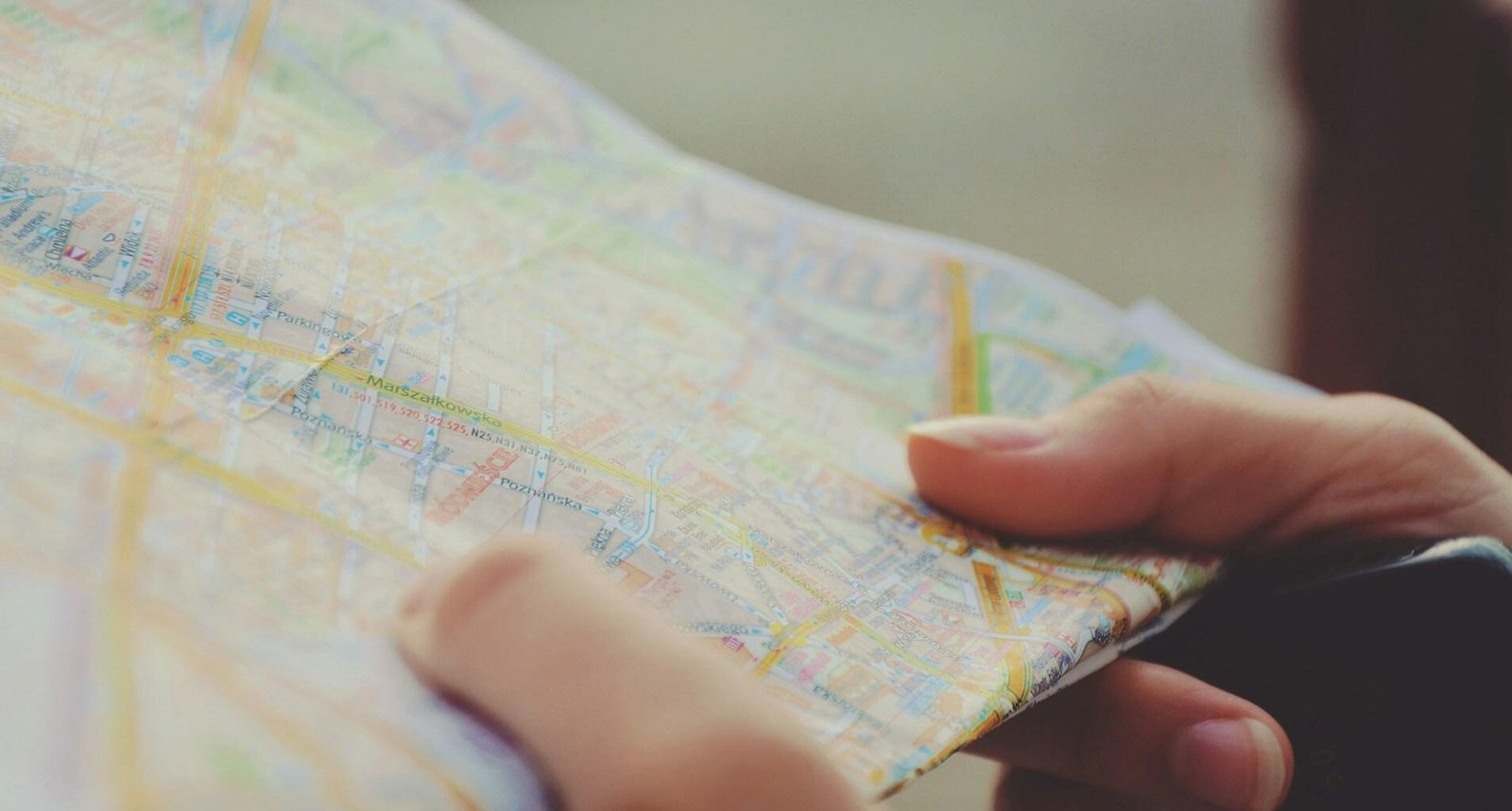 Person hält eine Landkarte in beiden Händen, aufgenommen im Freien, Symbol für Orientierung und Planung