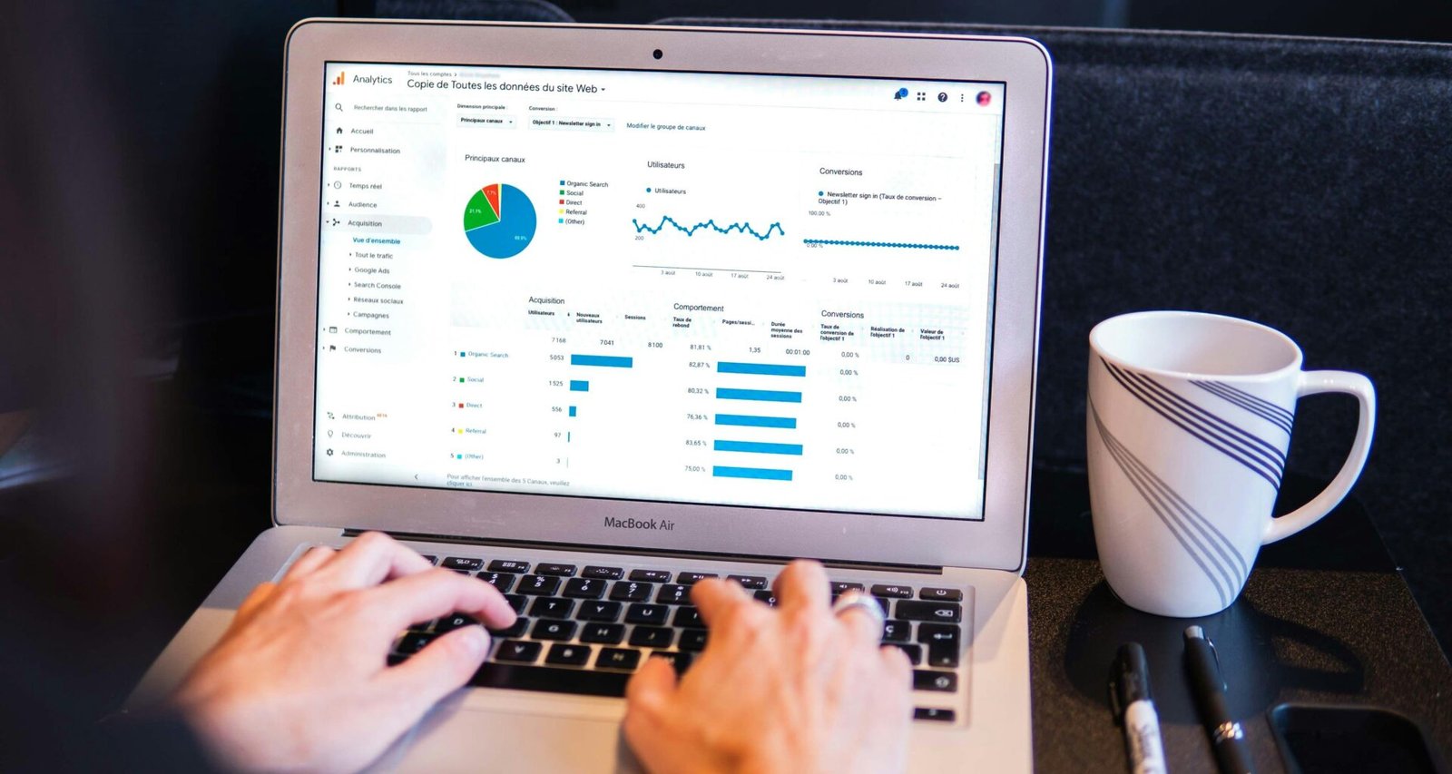Person tippt an einem MacBook Pro auf einem schwarzen Tisch, Fokus auf digitale Arbeit und moderne Technologien.