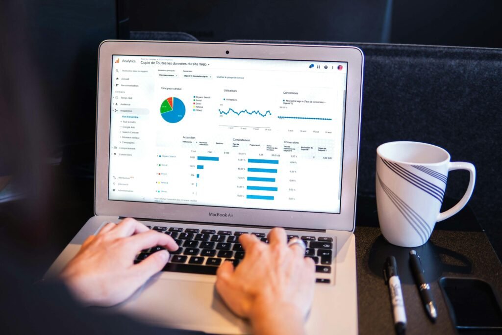 Person arbeitet an einem MacBook Pro auf einem schwarzen Tisch, Fokus auf Technik und digitale Produktivität.