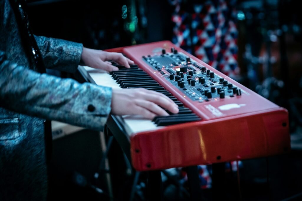 Person spielt auf einem rot-weißen Klavier in modernem Design, Fokus auf den Händen auf den Tasten.