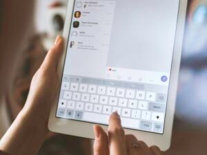 Person arbeitet mit einem weißen iPad und nutzt das Tablet für digitale Aufgaben in moderner Umgebung